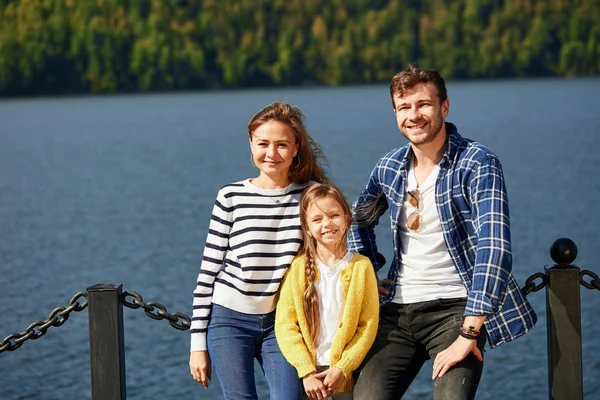 Щаслива сім'я дивиться на камеру, позує на пірсі на тихому озері — стокове фото
