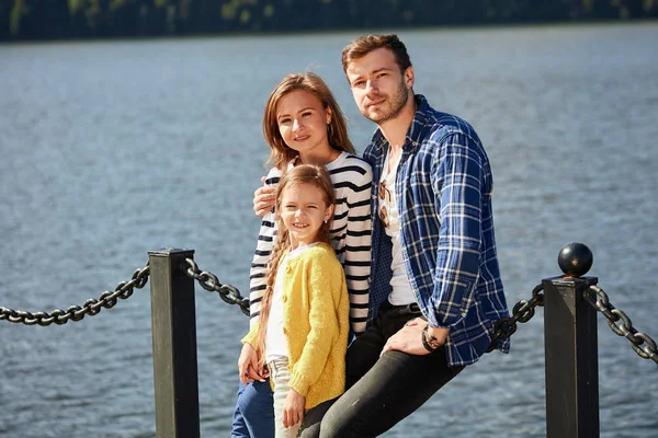 Família feliz olhando para a câmera enquanto posando no cais em lago tranquilo — Fotografia de Stock