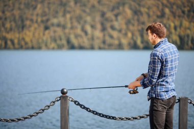 Nehir kenarında durup balık tutmaya çalışan balıkçılar.