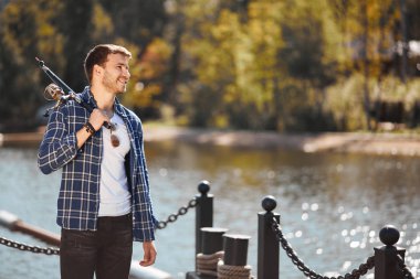 çubuk ve gölde balık tutma güneş gözlüğü ile genç balıkçı