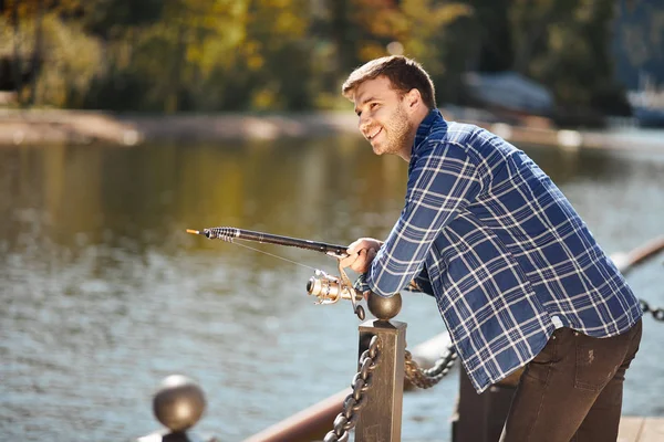 Jovem pescador com vara e óculos de sol pesca no lago — Fotografia de Stock