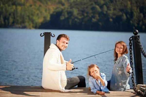 Família feliz com a filha de pesca na lagoa no outono — Fotografia de Stock
