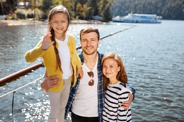 Família feliz olhando para a câmera enquanto posando no cais em lago tranquilo — Fotografia de Stock