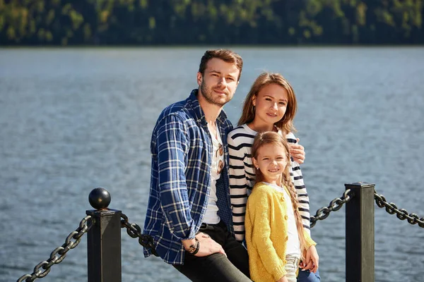 Happy Family looking at camera while posing on pier at quiet lake