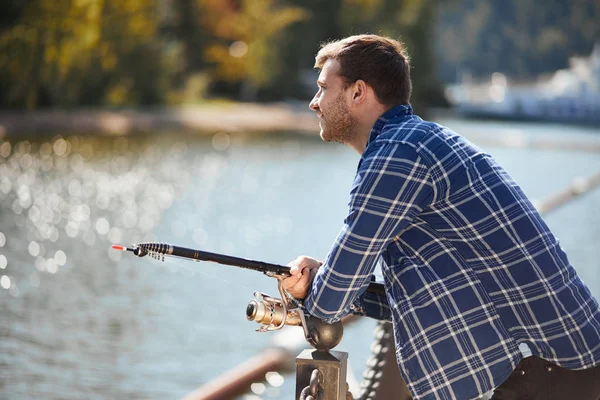 Pescador joven con caña y gafas de sol pescando en el lago — Foto de Stock
