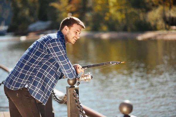 Jovem pescador com vara e óculos de sol pesca no lago — Fotografia de Stock
