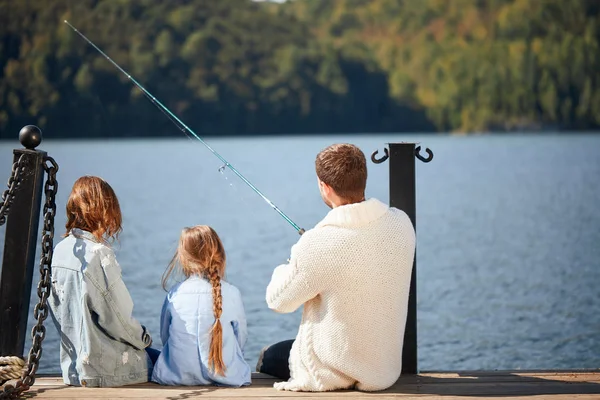 Famiglia felice con figlia pesca in stagno in autunno — Foto Stock