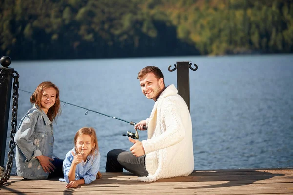 Щаслива сім'я з дочкою риболовля в ставку восени — стокове фото