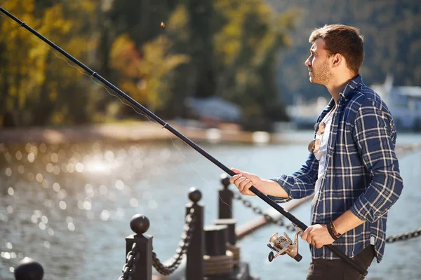 Nehir kenarında durup balık tutmaya çalışan balıkçılar.