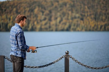 Nehir kenarında durup balık tutmaya çalışan balıkçılar.