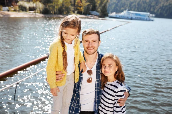 Família feliz olhando para a câmera enquanto posando no cais em lago tranquilo — Fotografia de Stock