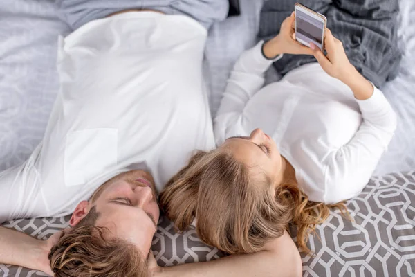 Atractiva chica rubia descansando con su novio en el dormitorio — Foto de Stock