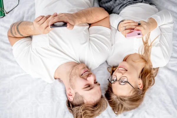 Drôle fou rire homme et femme regardant l'autre et en utilisant des gadgets — Photo