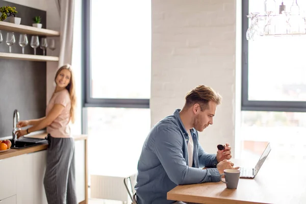 Aangename blonde kerel is een taart eten terwijl staren naar de laptop — Stockfoto