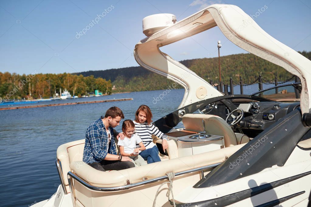 Family with daughter vacation together on sailboat in lake