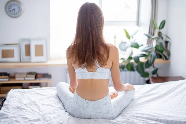 Vrouw mediteren in haar bed, achteraanzicht — Stockfoto