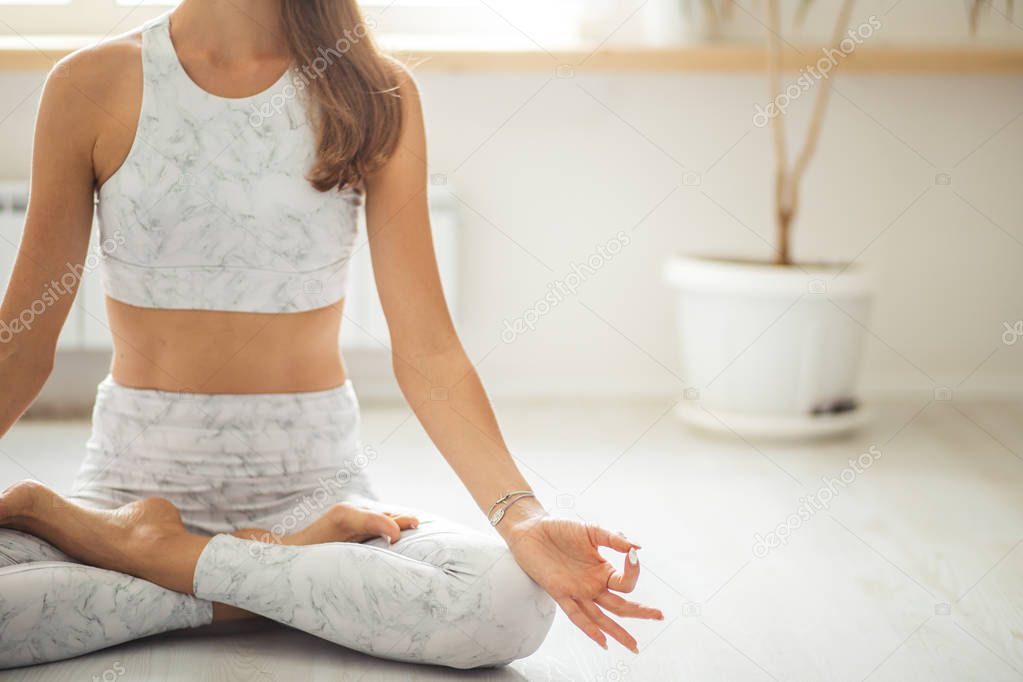 Sportive young woman in sportswear doing stretching while sitting on the floor at gym