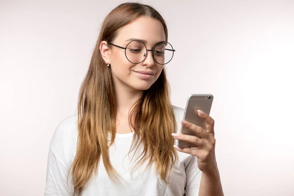 Jonge lachende blonde vrouw met behulp van telefoon geïsoleerd op witte achtergrond — Stockfoto