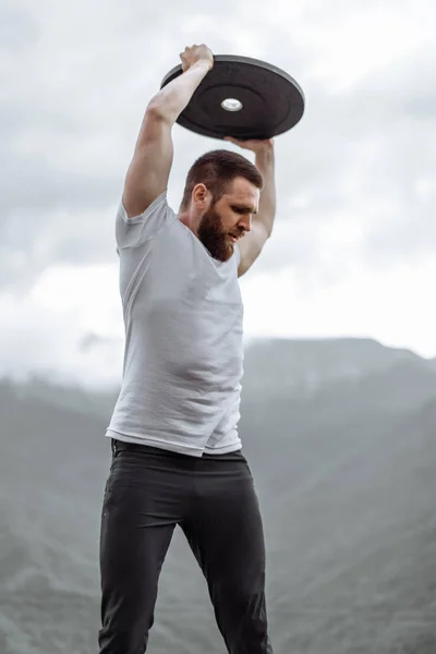 Guapo musculoso hombre guapo mirando montañas desde la cima. — Foto de Stock