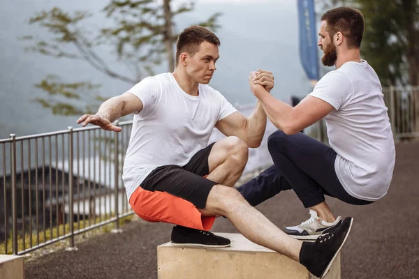 Muskulat killar visar ett ben knäböj motion, närbild, utomhus träning — Stockfoto