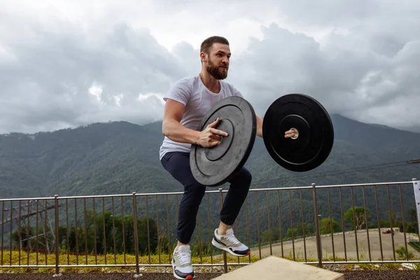 Fuerte atleta masculino haciendo saltos de caja con dos placas al aire libre en la cima de la montaña. — Foto de Stock