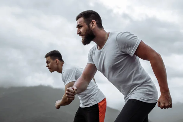 Entrenamiento temprano en la mañana, hombres deportivos corriendo por las montañas viviendo un estilo de vida saludable — Foto de Stock