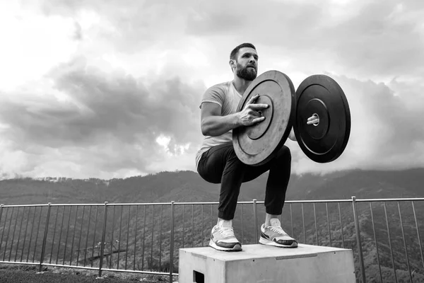 Forte atleta maschio che fa salti box con due piastre all'aperto in cima alla montagna. — Foto Stock