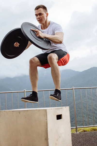 Fuerte atleta masculino haciendo saltos de caja con dos placas al aire libre en la cima de la montaña. — Foto de Stock