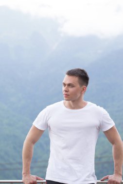 Yakışıklı kaslı adam tepeden dağlara bakıyor..