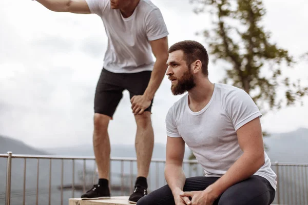 Dos atletas descansan después de un intenso entrenamiento al aire libre en el paisaje de montaña — Foto de Stock