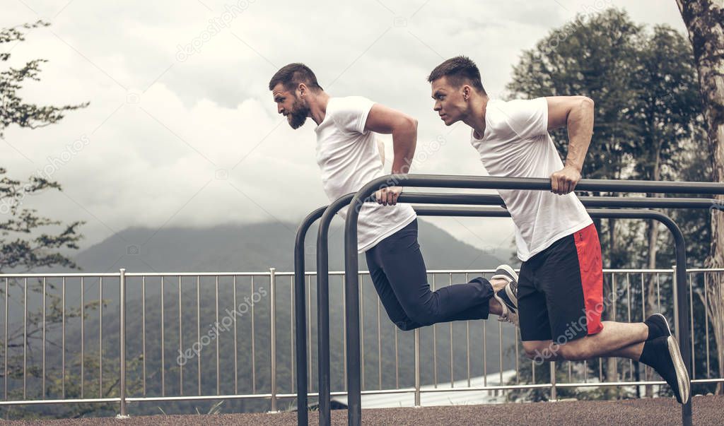 Two sportsmen doing dips on parallel bars