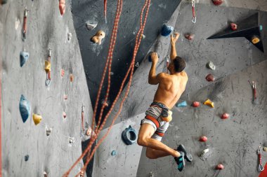 Kapalı bir tırmanma merkezinde panoramik bir adam kaya kayası yapıyor..