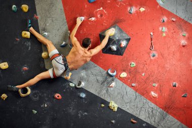 Erkek profesyonel dağcı, kayalık merkezde kapalı alanda çalışıyor..