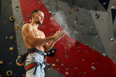 Climber coating his hands in powder chalk magnesium to climb indoor, close-up clipart