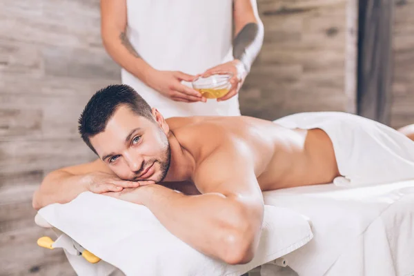 Knappe beaded man liggend op een massagetafel in spa salon — Stockfoto