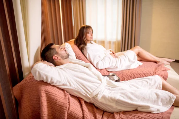 happy man is lying on the bed and sleeping while his wife sitting with pensive look