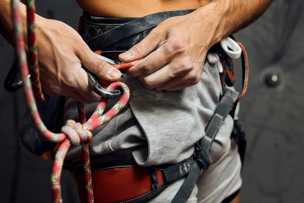 Klättrarens manliga händer med utrustning under förberedelse för klättring, närbild. — Stockfoto