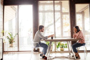 Çift fikir paylaşıyor, büyük pencerenin karşısında oturuyor..