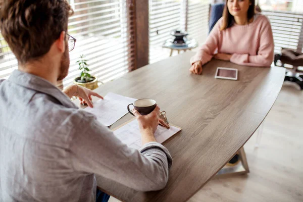 Een man en een vrouw zitten tegenover elkaar aan een tafel. — Stockfoto