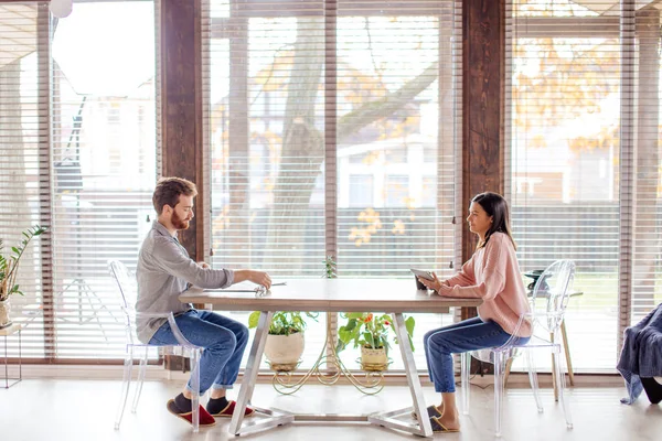 Um homem e uma mulher estão sentados em uma mesa oposta um ao outro . — Fotografia de Stock