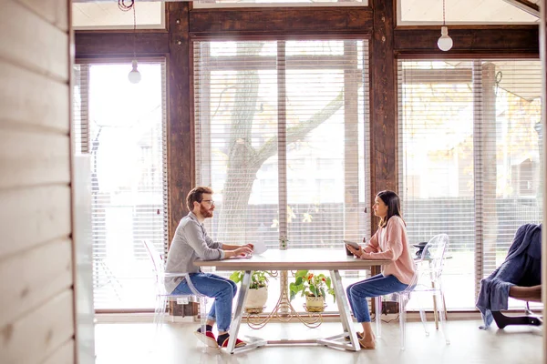 Un hombre y una mujer están sentados en una mesa uno frente al otro. — Foto de Stock