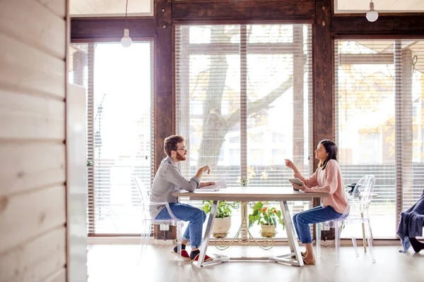 Un hombre y una mujer están sentados en una mesa uno frente al otro. — Foto de Stock