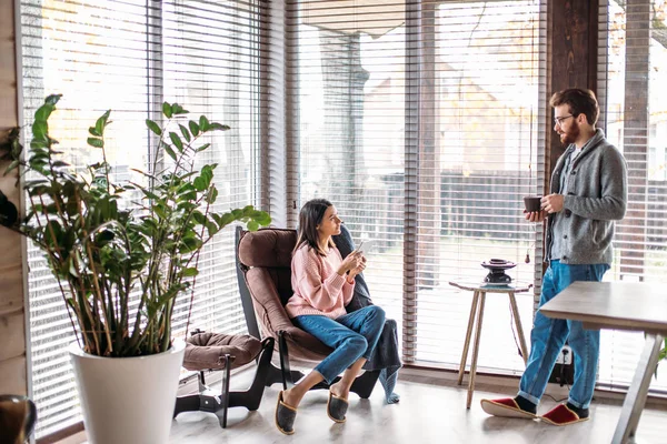 Paar in Küche verbringt Zeit mit Tasse Kaffee und Smartphone — Stockfoto