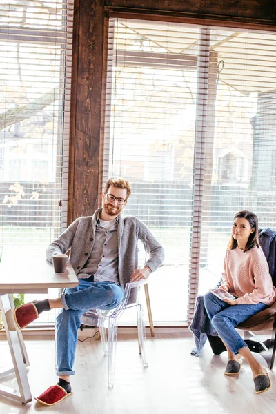 Pareja en la cocina pasar tiempo junto con una taza de café y teléfono inteligente —  Fotos de Stock