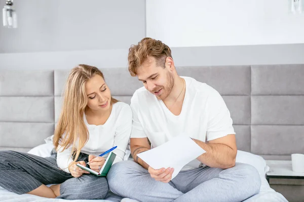 Gelukkige aantrekkelijke paar schrijven op een notitieblok in huis — Stockfoto