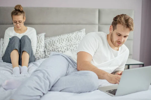 Schöner blonder Mann surft im Netz, während seine Frau E-Books liest. — Stockfoto