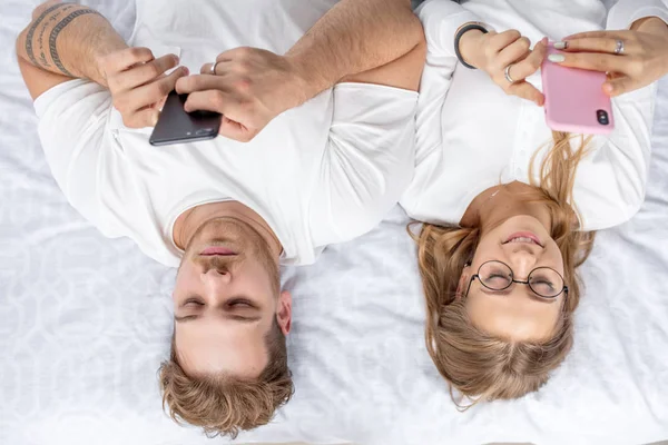 Familia joven usando sus teléfonos móviles antes de dormir — Foto de Stock