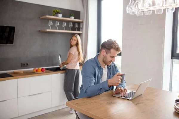 Jonge knappe man met de laptop terwijl zijn vrouw hem terug kijken kralen — Stockfoto