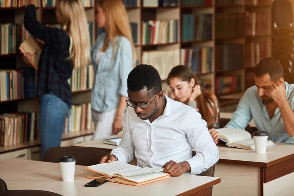 Africká americká mužský college studen, příprava na zkoušky v knihovně. — Stock fotografie