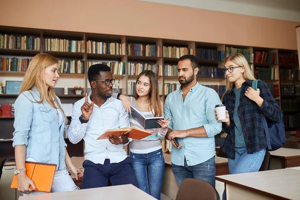 Estudiantes multirraciales se divierten en la biblioteca mientras se preparan para los exámenes . — Foto de Stock